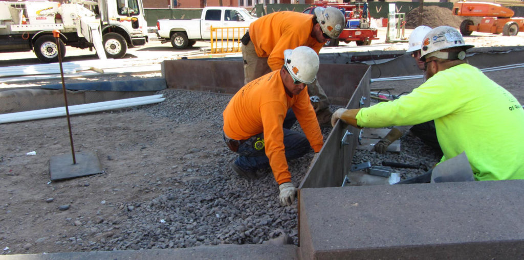 Image of construction workers installing a metal planter.